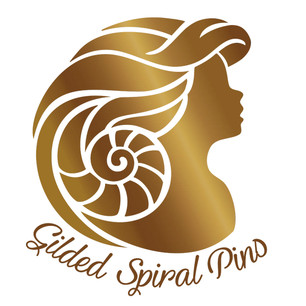 A gold and white logo featuring a stylized profile of a woman's head with flowing hair and a spiral shell motif, with the text 'Gilded Spiral Pins' below on a white background.